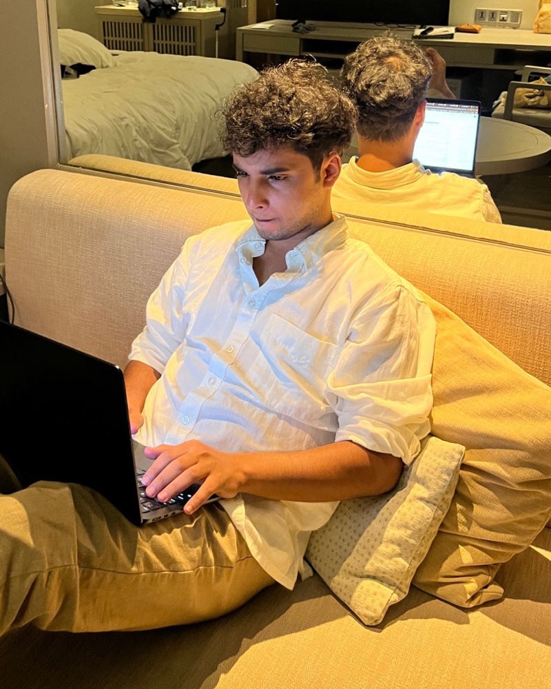 Navneet Jha working on his laptop on a sofa, wearing a white linen shirt